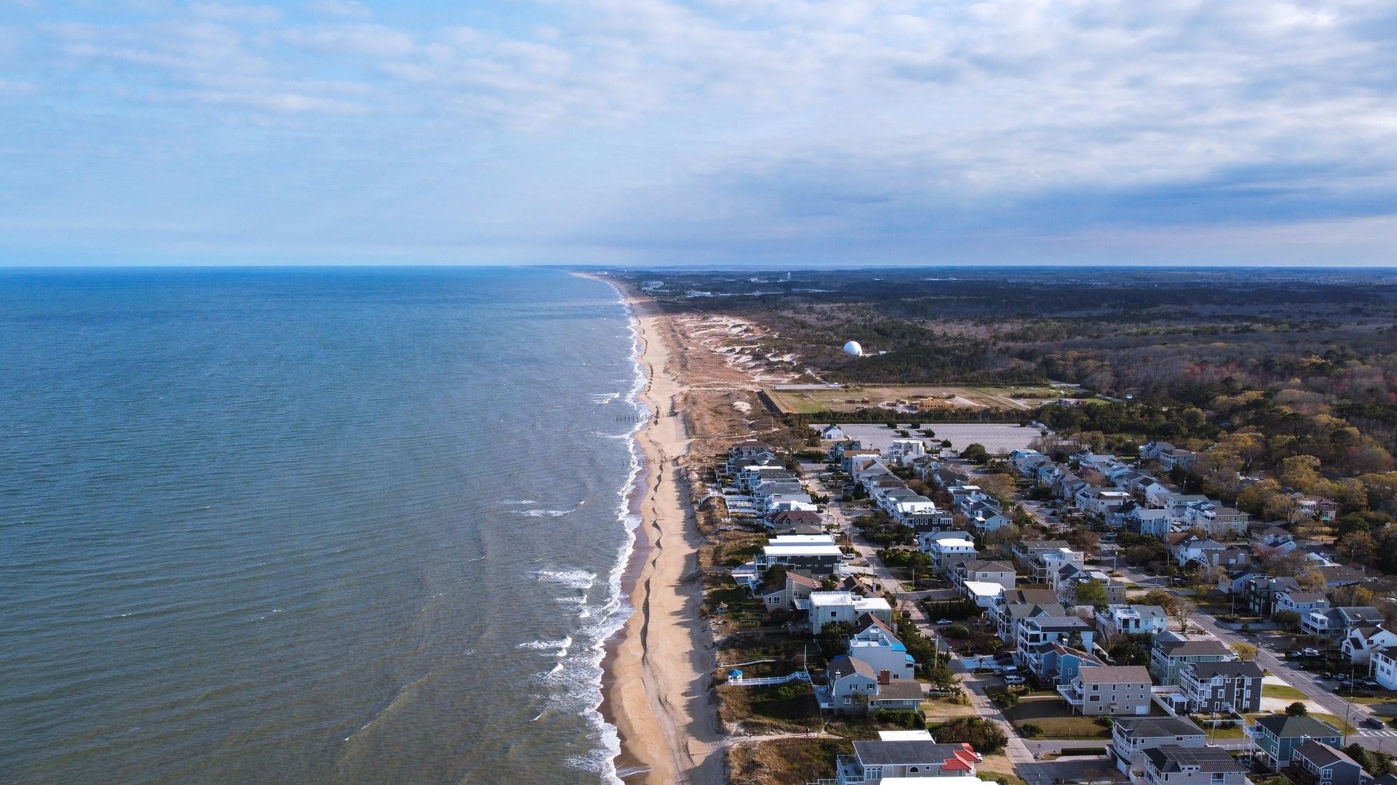 A beach with houses and trees.