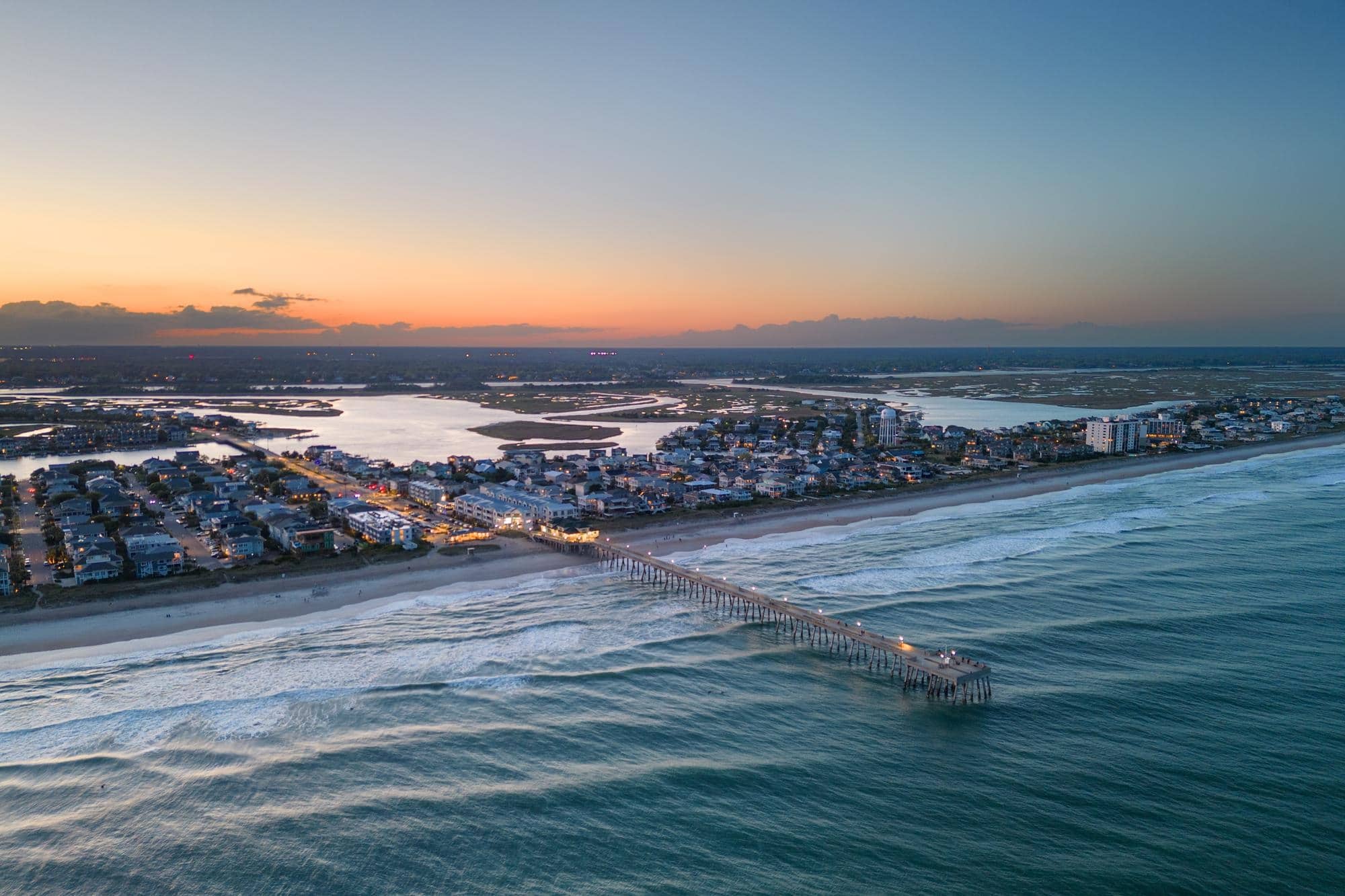 A long pier stretching out over a beach.