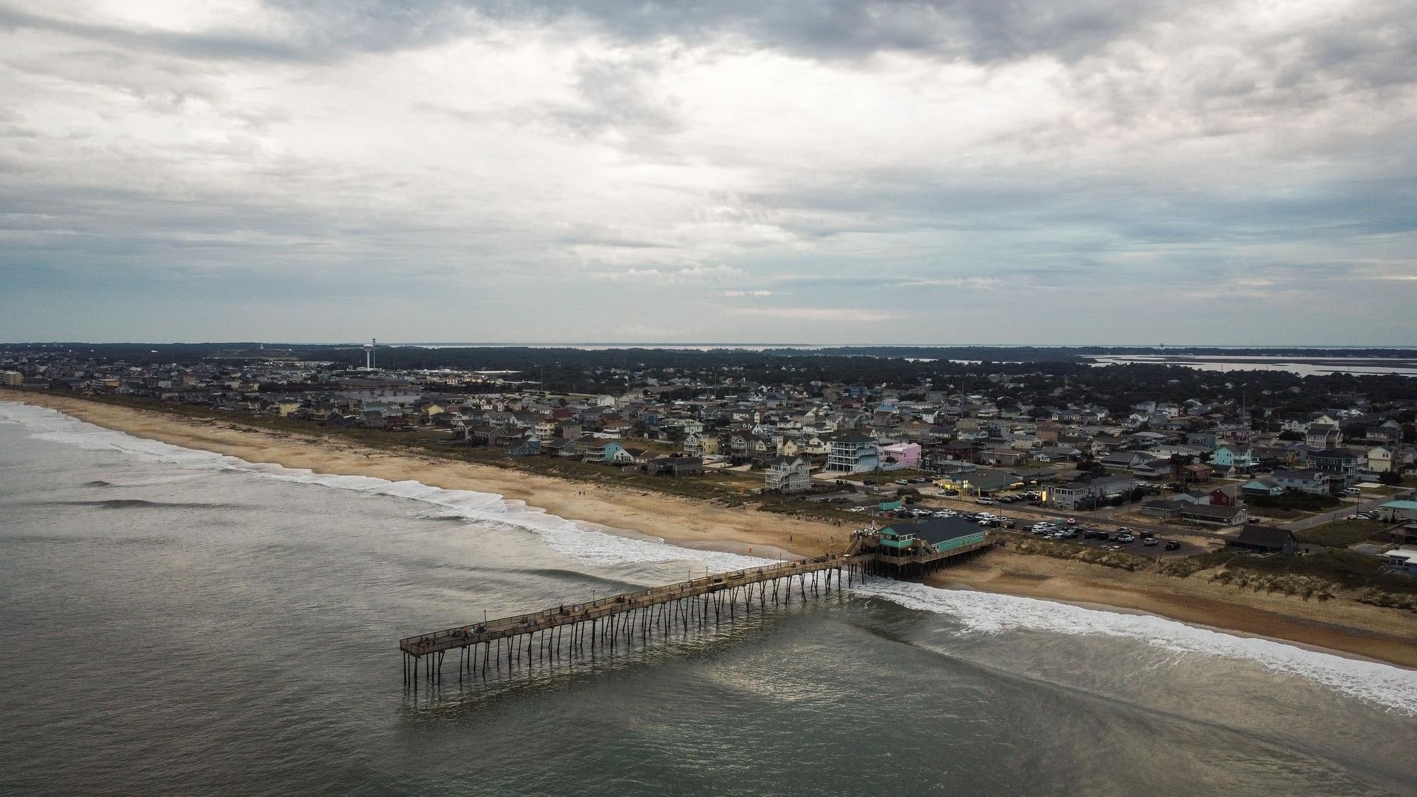 A city next to the beach with a pier in view.