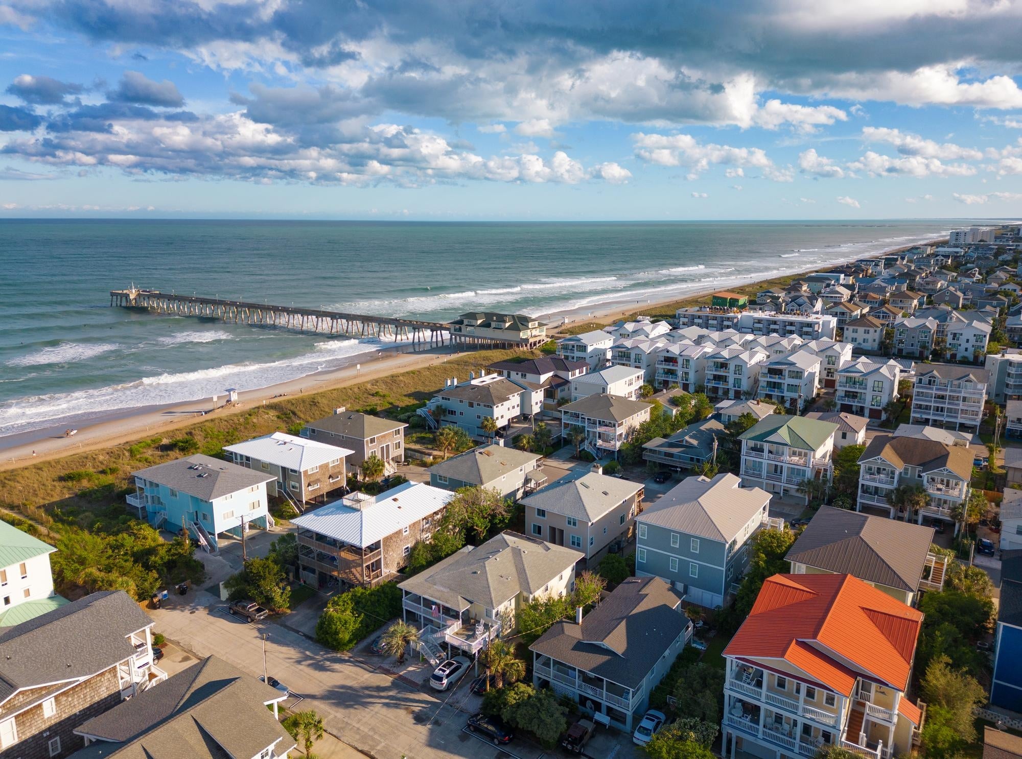 A beach town next to the water, with a small pier in view.